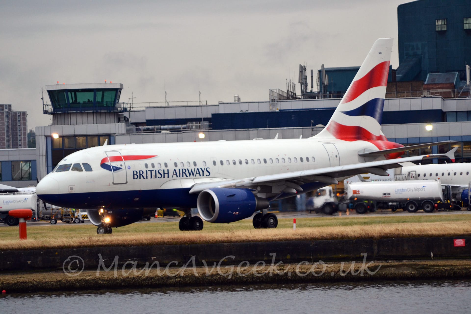 Side view of a white, twin engined jet airliner with a dark blue belly and engine pods