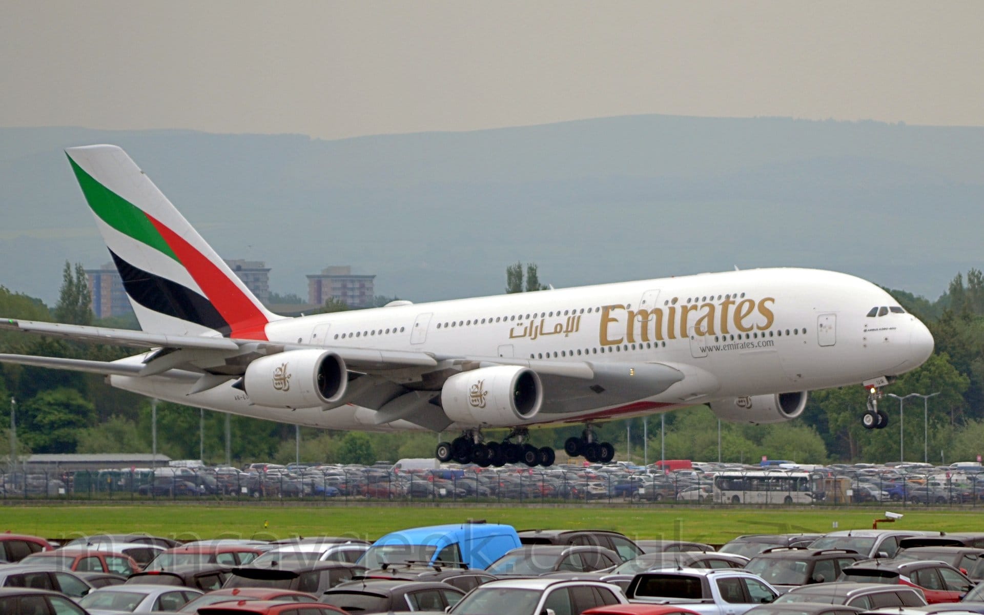 Side view of a very large, white, 4 engined jet airliner flying from left to right at a very low altitude