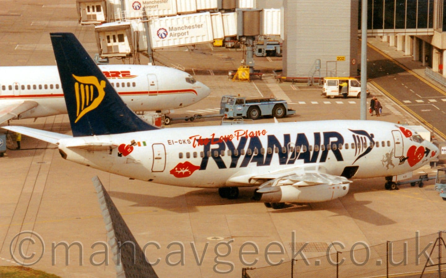 Side view of a white, twin engined jet airliner parked facing to the righte.