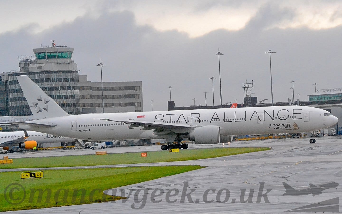 Side view of a twin engined jet airliner taxiing from left to right.