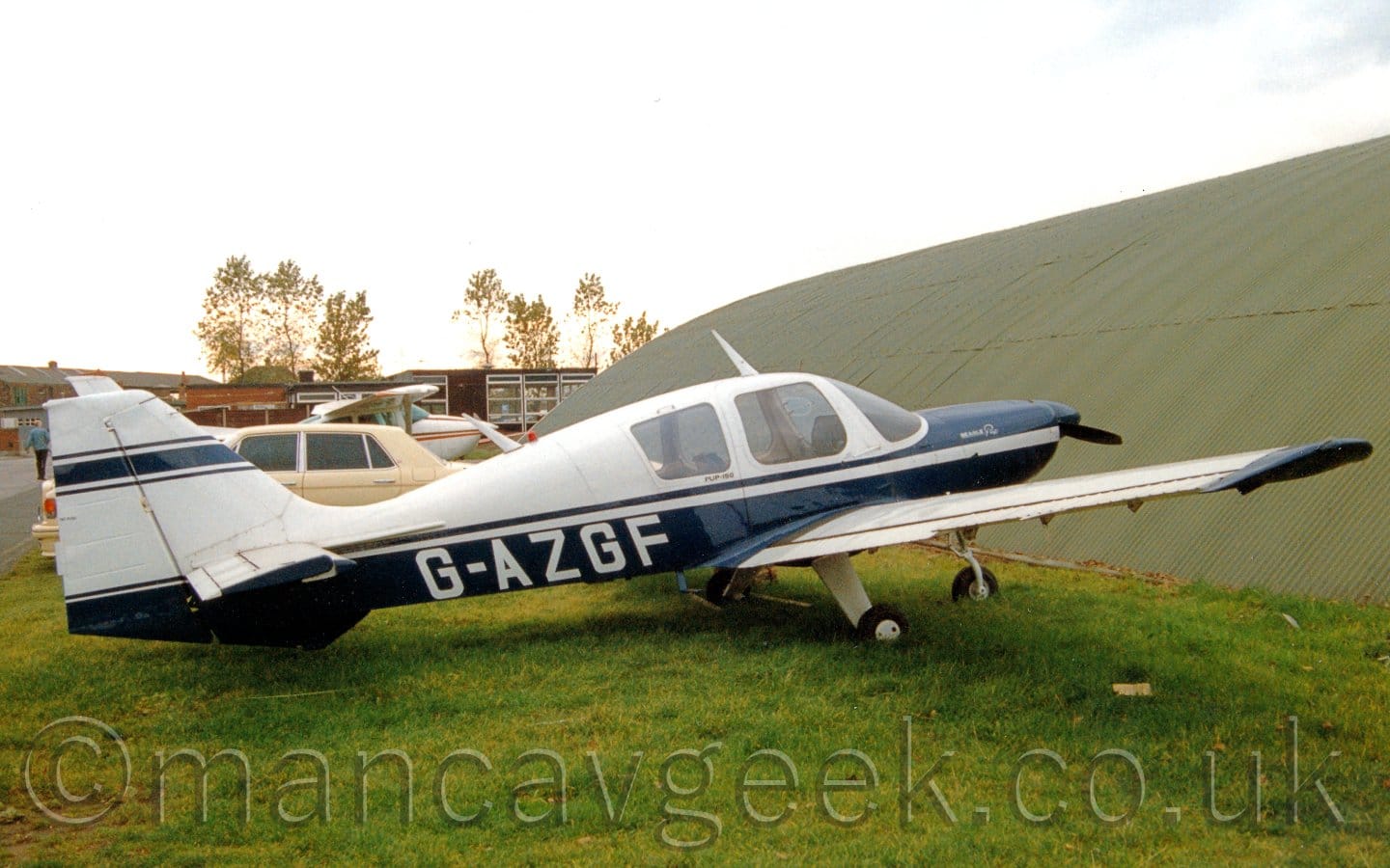 Side view of a single engined light aircraft parked on grass facing to the right.