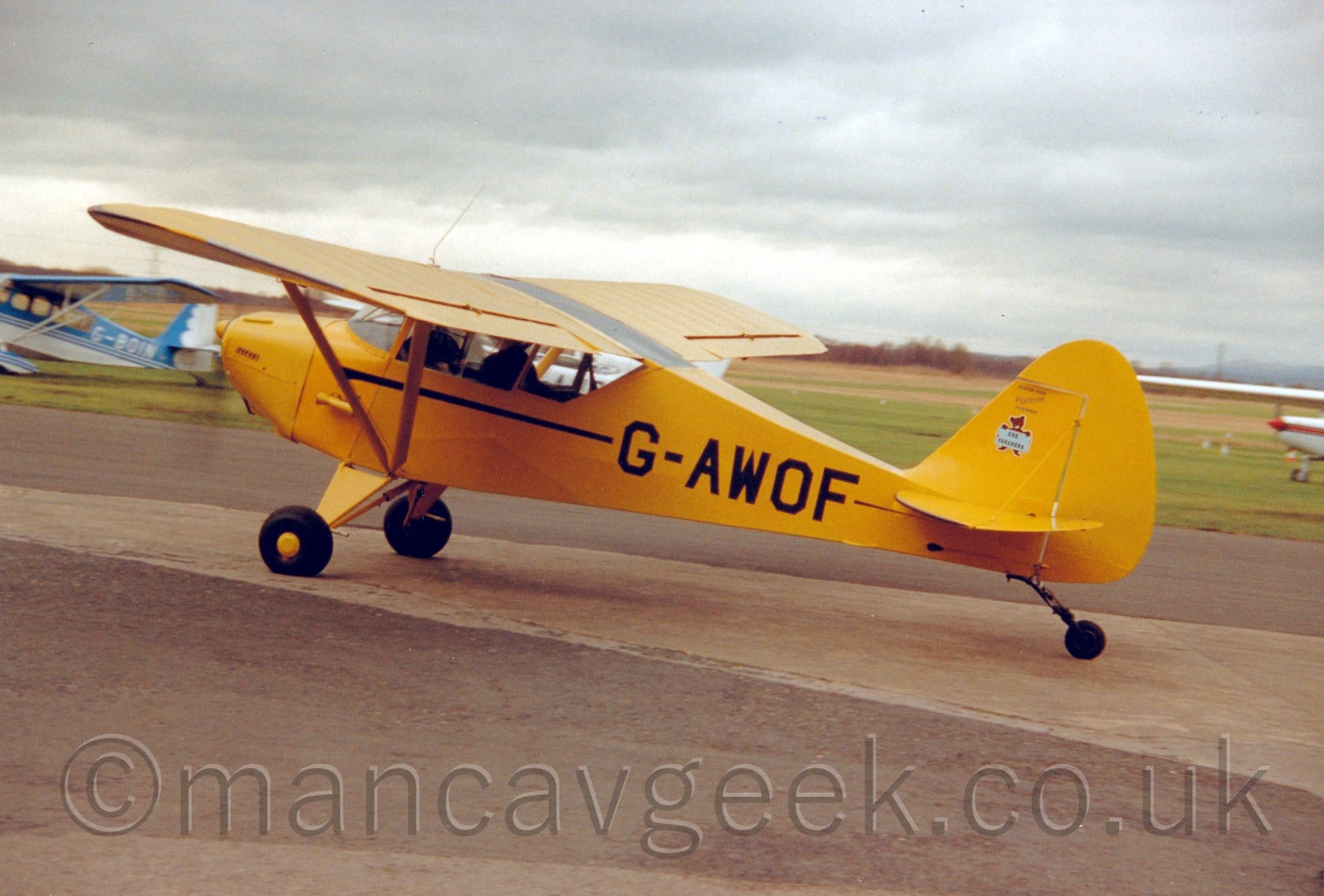 Side view of a high-winged, single engined light aircraft taxiing from right to left.