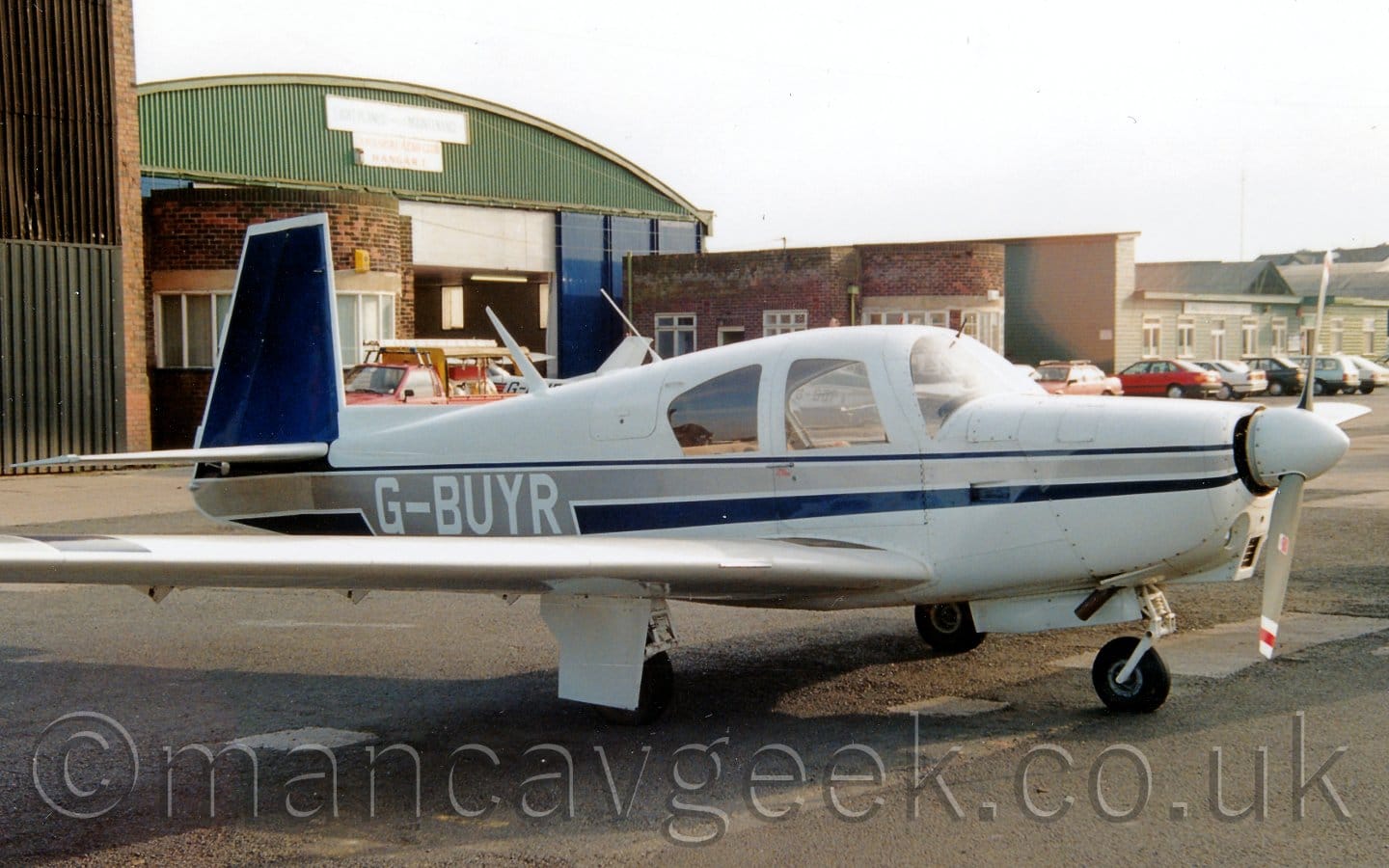 Side view of a single engined light aircraft parked on black tarmac facing to the right.