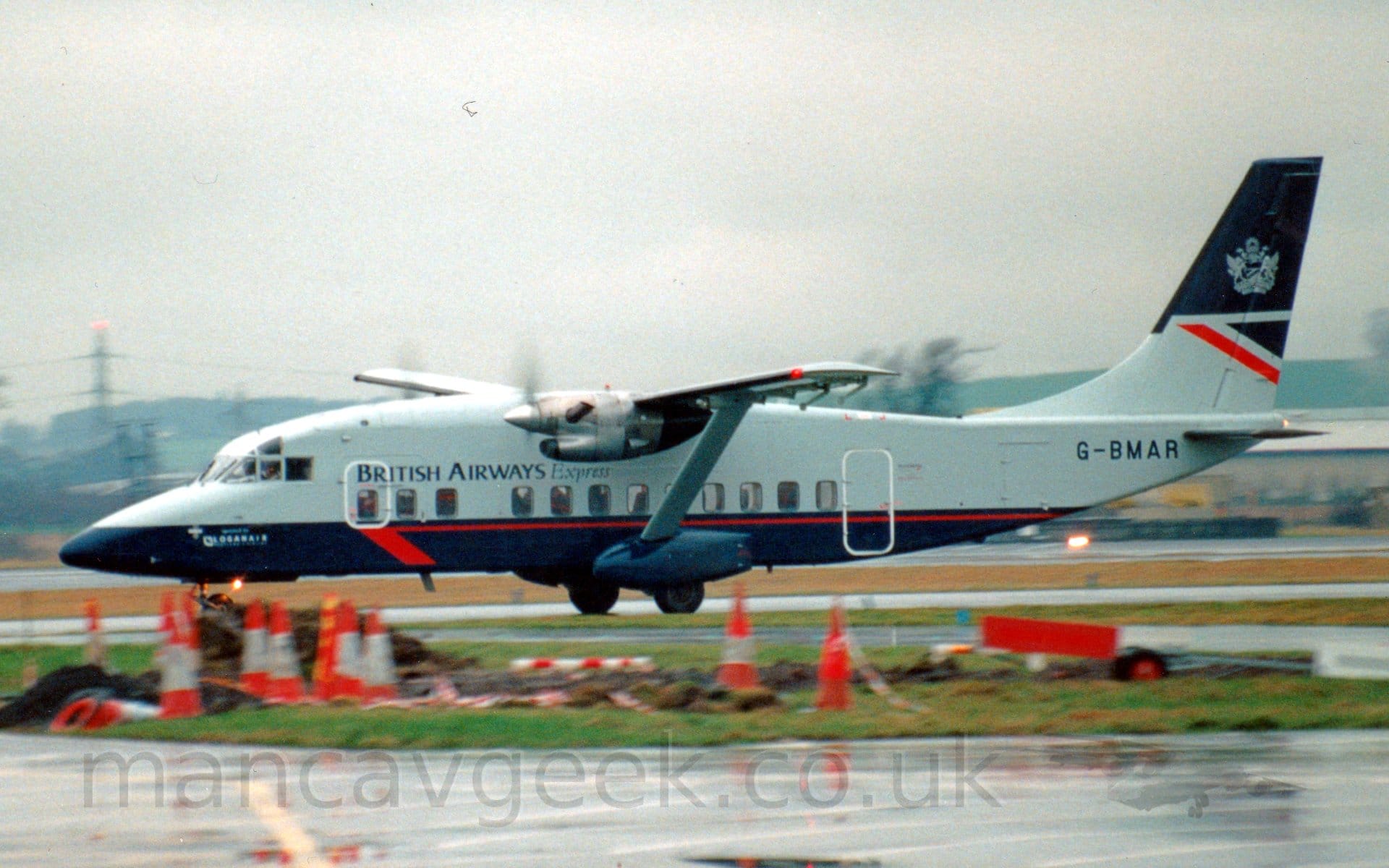 Side view of a high-winged, twin propellor-engined airliner taxiing from right to left.