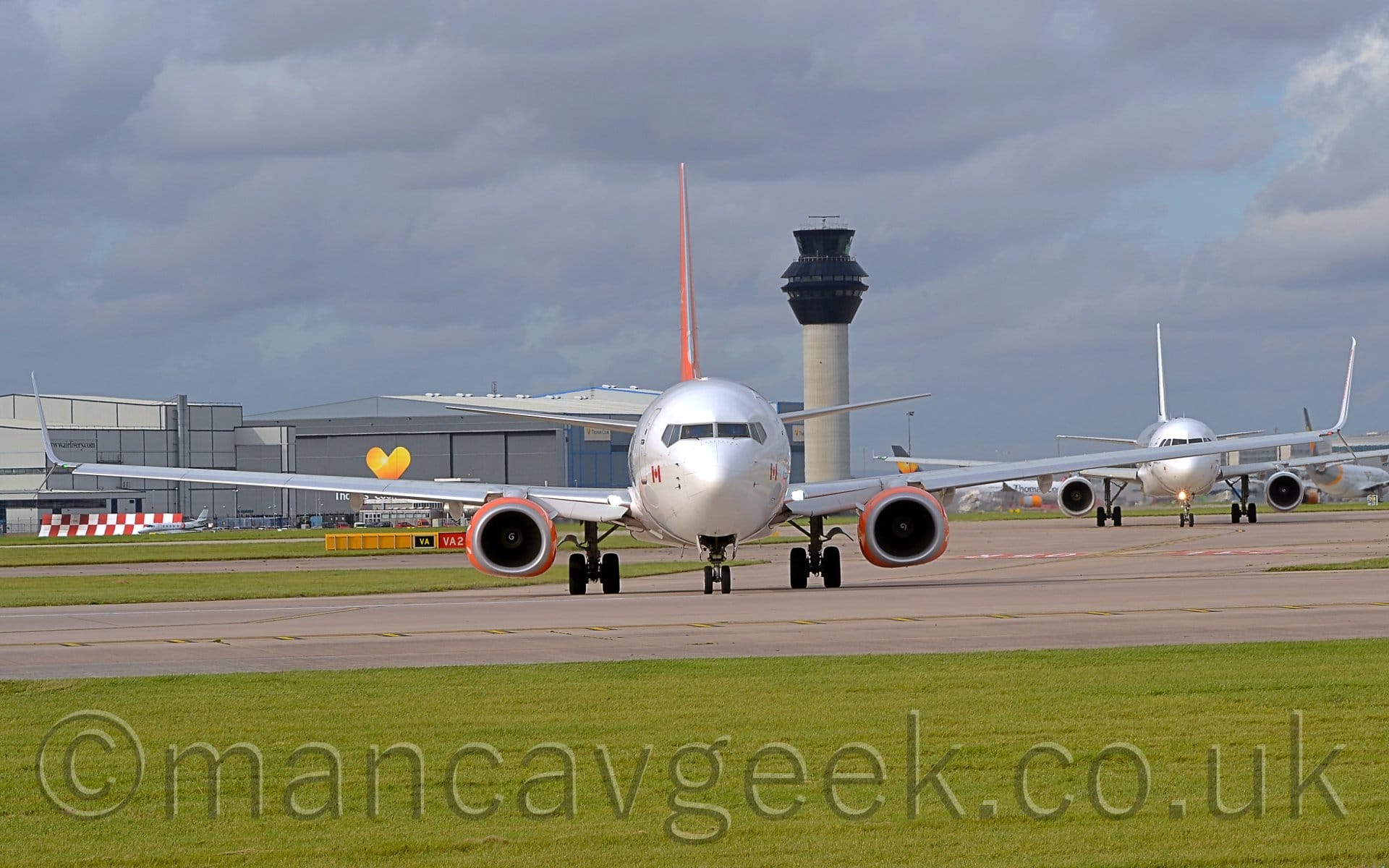 Head-on shot of a white, twin-engined jet airliner taxiing almost directly towards the camera.