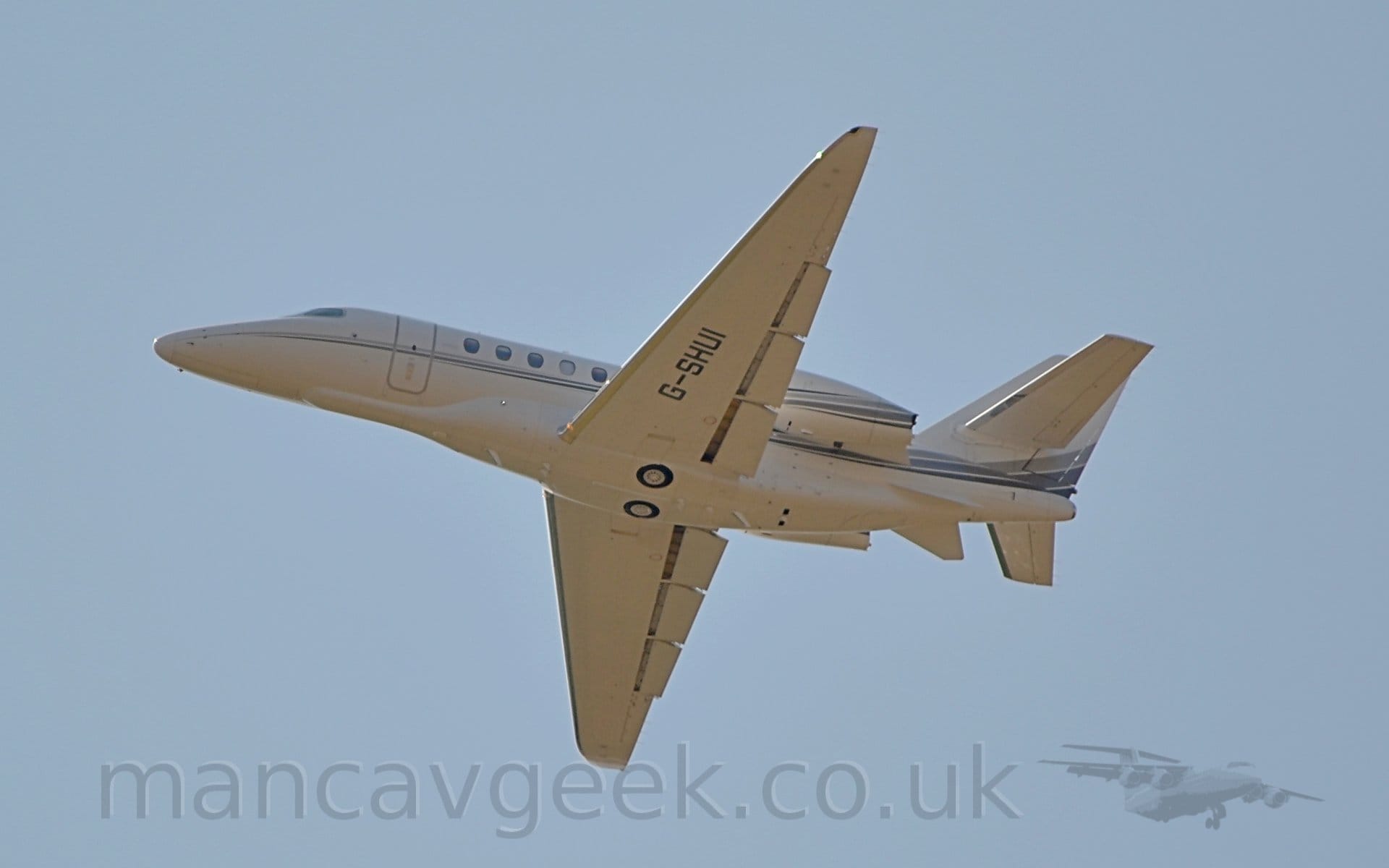 Low side view of a twin engined BizJet flying from right to left at a very low altitude