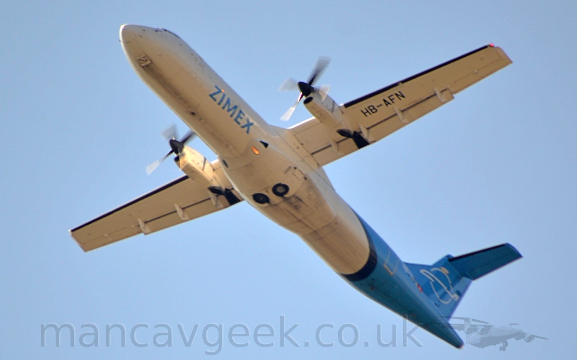 Low side view of a high-winged, twin propellor-engined airliner flying from right to left at a low altitude