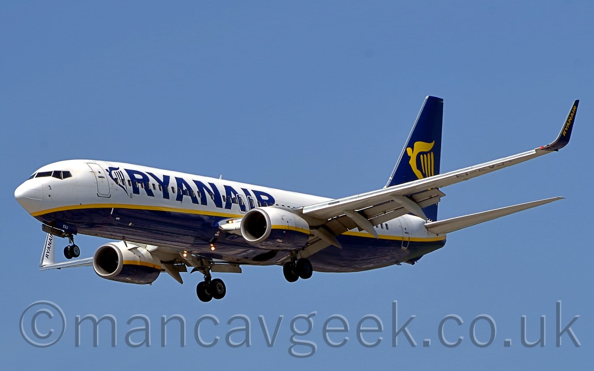 Side view of a twin engined jet airliner flying from right to left at a very low altitude in a blue sky