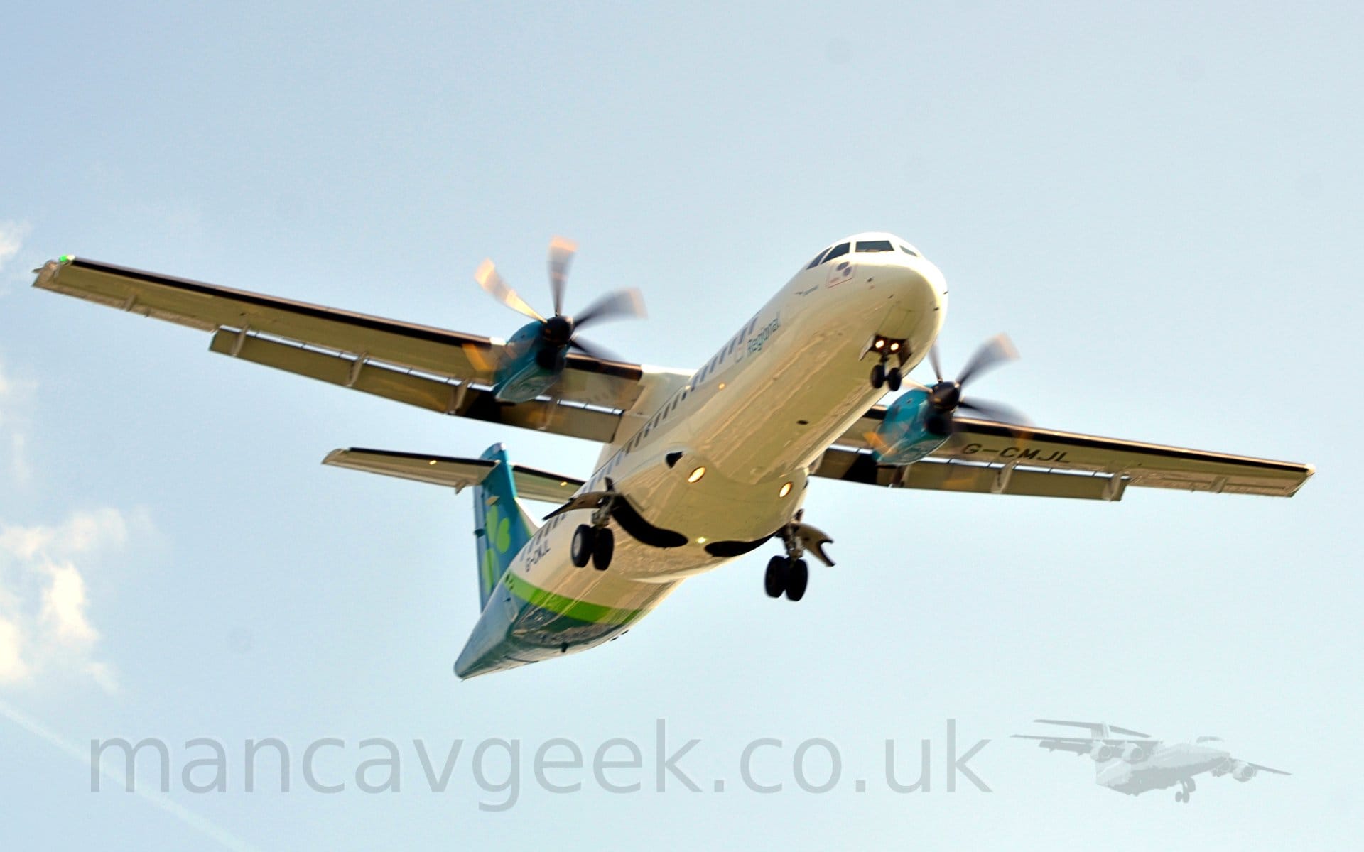Low front view of a high-winged, twin propellor-engined airliner flying from left to right at a very low altitude