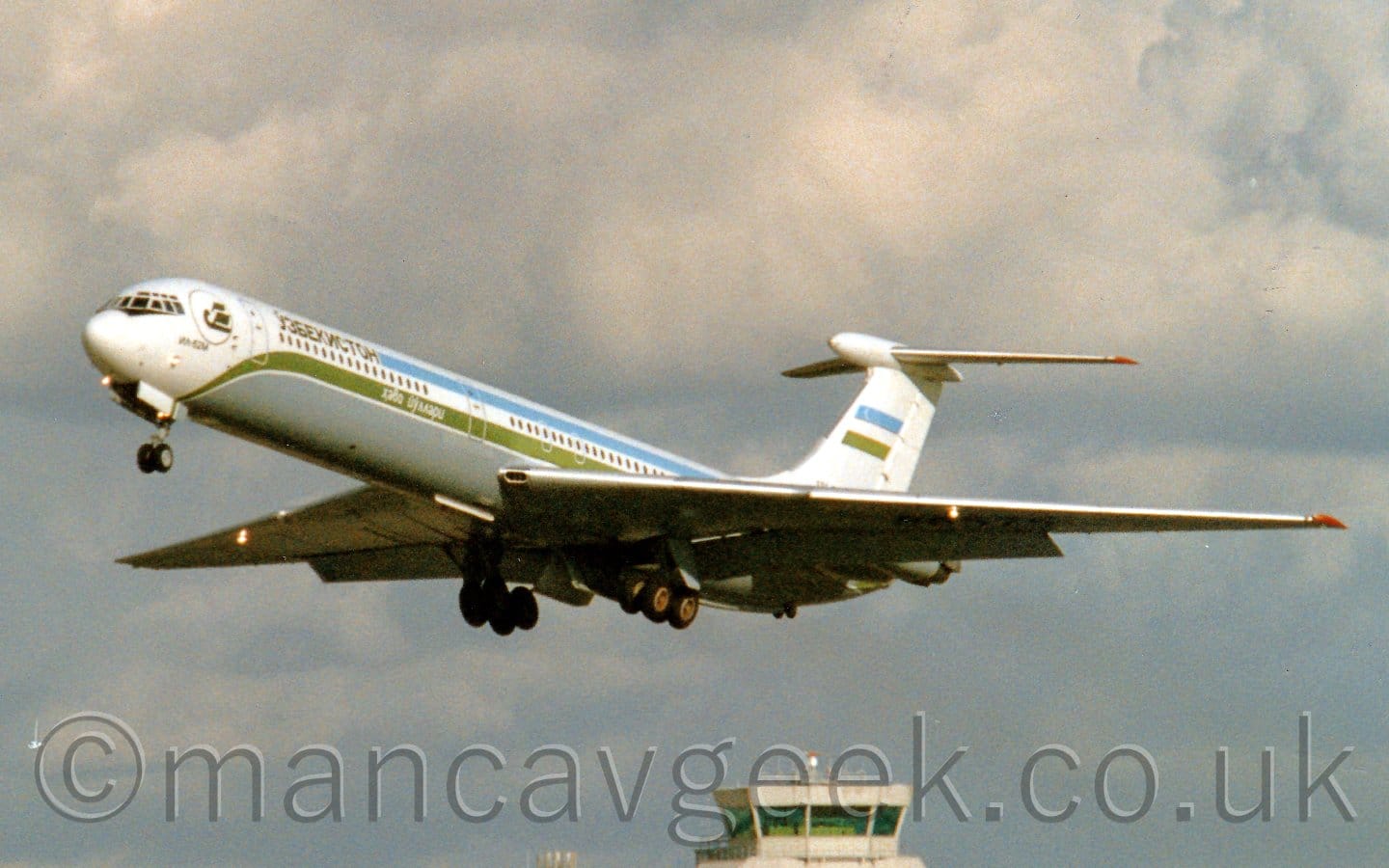Side view of a 4 engined jet airliner with the engines mounted in pairs  on the rear fuselage, flying from left to right at a low altitude