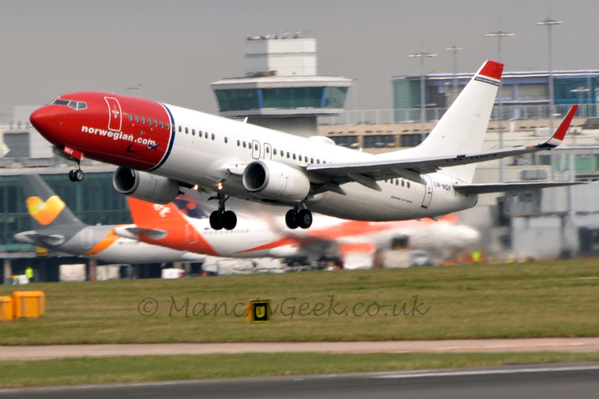 Side view of a twin engined jet airliner flying from right to left at a very low altitude