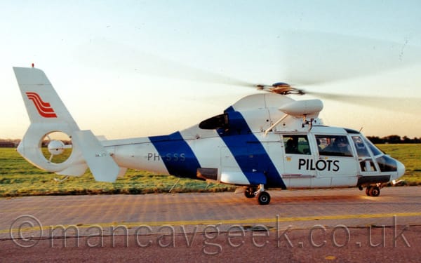 Side view of a white helicopter ground-taxiing from left to right.