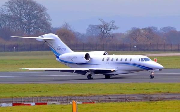 Side view of a white, 2 engined BizJet with the engines mounted on the sides of the rear fuselage.