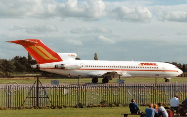 Side view of a white, three-engined jet airliner with the engines mounted on the rear fuselage, taxiing from left to right.