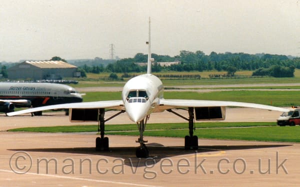 Front view of a very pointy, long, and thin white, 4 engined jet airliner with slightly down-turned wings