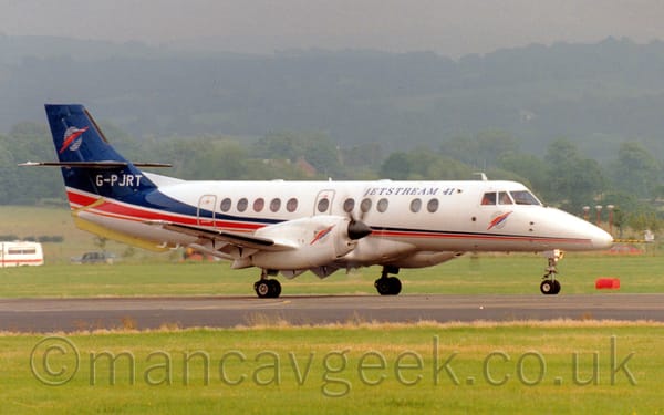 Side view of a white, twin engined jet airliner taxiing along a runway from left to right