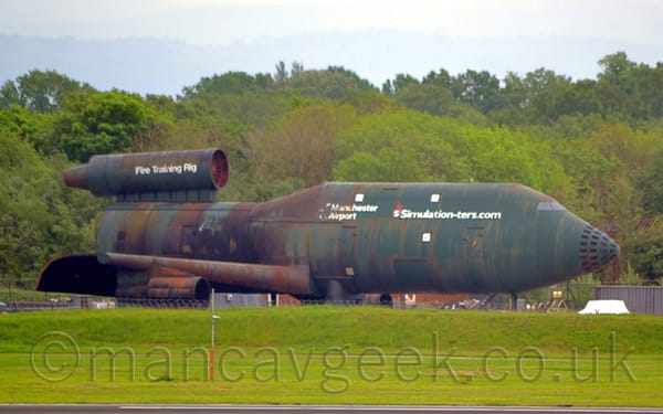 Photo of a green, but badly corroded, Fire Training Rig, used for fire training, facing to the right
