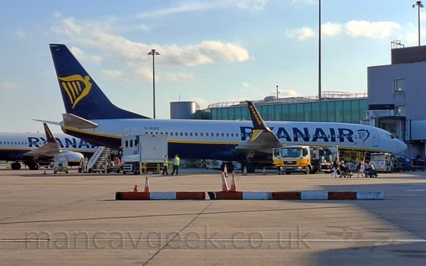 Slightly grainy side view of a white, twin engined jet airliner parked facing to the right.
