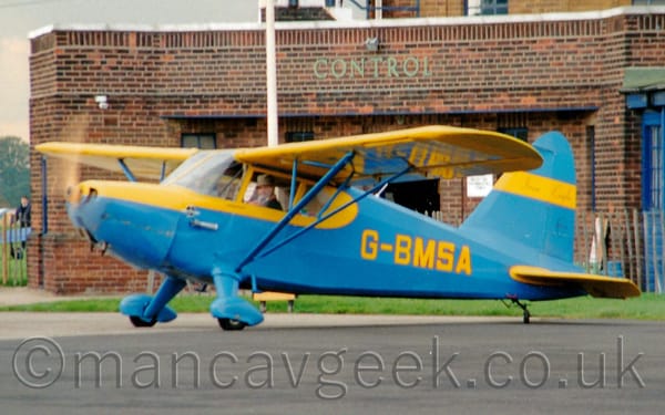 Side view of a blue, high-winged, single-engined light aircraft taxiing from right to left