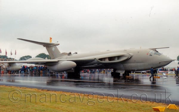Side view of a surprisingly sleek, sandy brown, 4 engined jet bomber aircraft, parked facing to the right.
