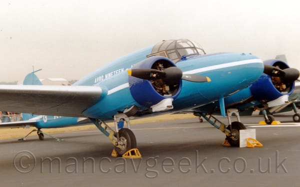 Side view of a blue, twin propellor-engined, World War 2-era transport aircraft parked facing to the right.