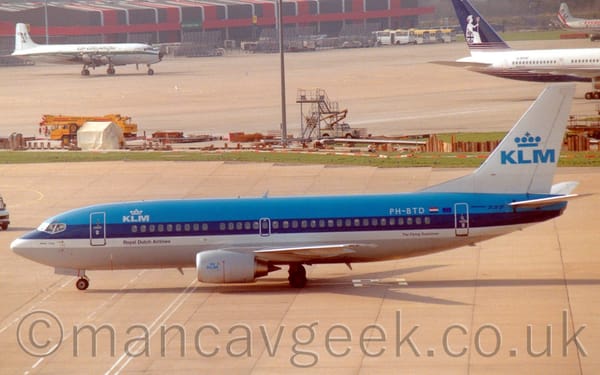 Side view of a blue, twin engined jet airliner taxiing from right to left.