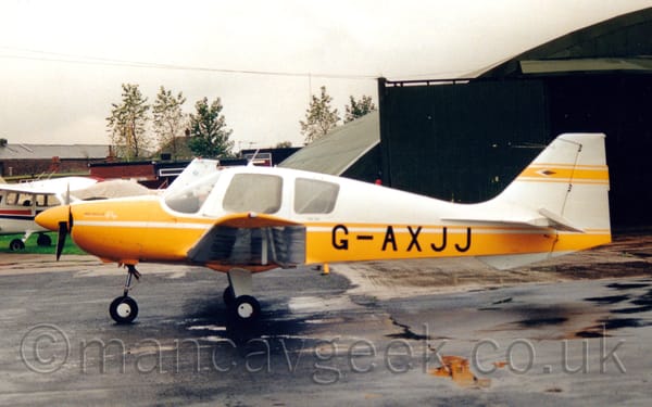 Side view of a white and yellow, single-engined light aircraft parked facing to the left.
