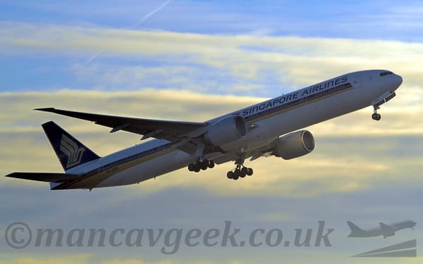 Side view of a white, twin engined jet airliner flying from right to left at a low altitude, just after taking off.