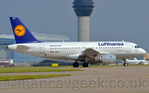Side view of a white, twin engined jet airliner taxiing from left to right.