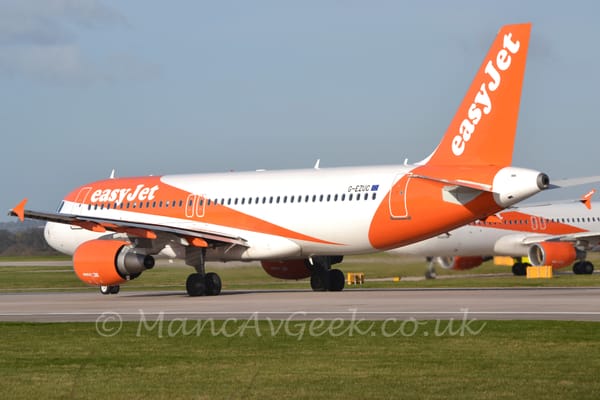 Side view of a twin engined jet airliner rolling from right to left along a grey runway.