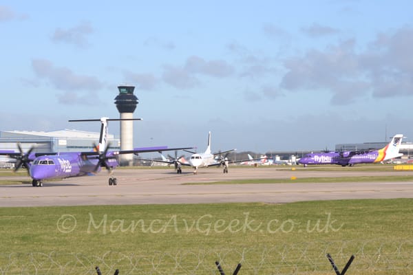 3 different types of airliner in 2 different colour schemes taxiing from right to left at a busy airport.