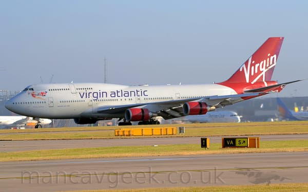 Side view of a very large, white, 4 engined jet airliner moving from right to left .