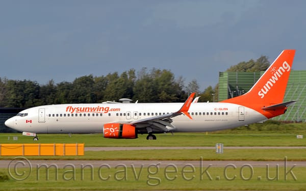 Side view of a white and orange, twin engined jet airliner moving from right to left.