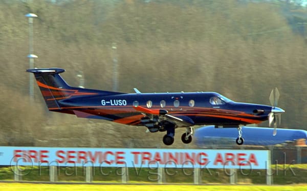 Side view of a black, single engined BizProp flying from left to right at a very low altitude
