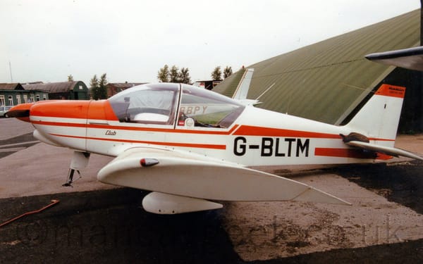 Side view of a single-engined light aircraft parked facing to the left, with it's tail weighed down so it's nose, minus the nose-wheel, is raised in the air.
