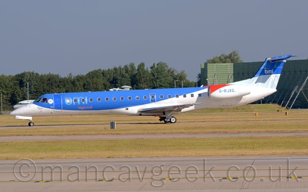 Side view of a twin engined jet airliner with the engines mounted on the sides of the rear fuselage, taxiing from right to left along a grey taxiway.