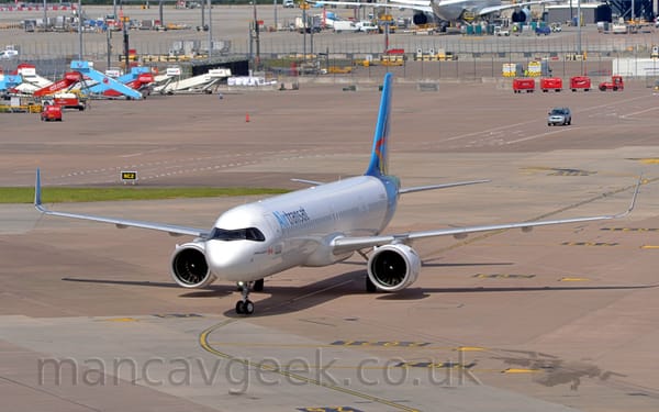 Side view of a twin engined jet airliner taxiing from right to left.