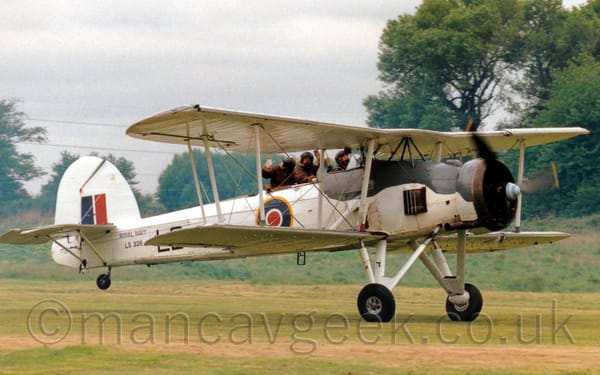 Side view of a large, single-engined bi-plane rolling along a grass runway with it's tail-wheel raised into a flying position.