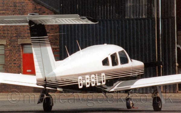 Rear side view of a single-engined light aircraft parked facing to the right and away from the camera.