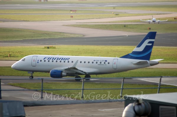 Side view of a white, twin engined jet airliner taxiing from right to left.