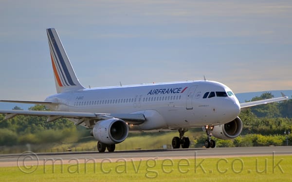 Side view of a twin engined jet airliner decelerating, moving from left to right. The plane is mostly white, with blue "Air France" titles on the upper forward fuselage.