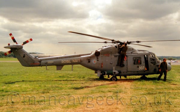 Side view of a grey military helicopter parked on grass facing to the right.