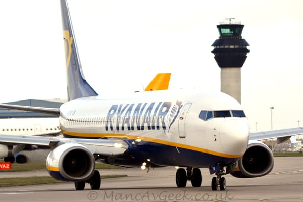 Front view of a twin engined jet airliner taxiing from left to right and slightly towards the camera.