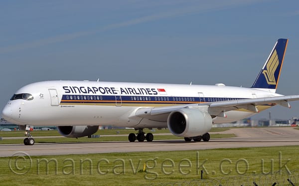 Side view of a twin engined jet airliner taxiing from right to left on a grey runway.