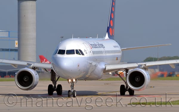 Side view of a twin engined jet airliner taxiing from right to left. The plane has a white top half, and a grey bottom.