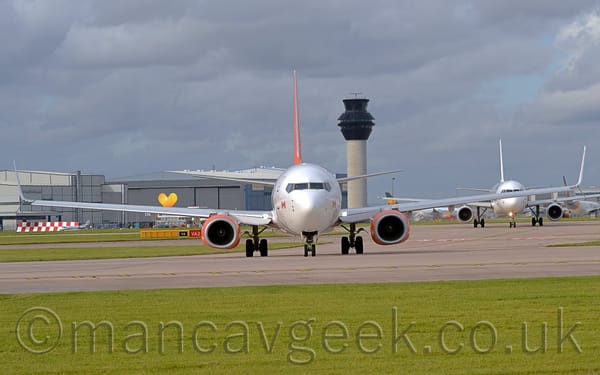 Head-on shot of a white, twin-engined jet airliner taxiing almost directly towards the camera.