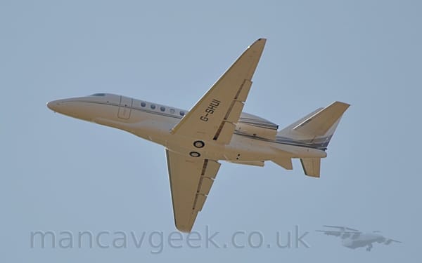 Low side view of a twin engined BizJet flying from right to left at a very low altitude