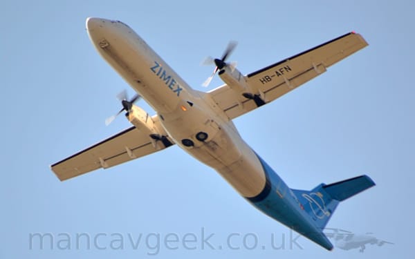 Low side view of a high-winged, twin propellor-engined airliner flying from right to left at a low altitude