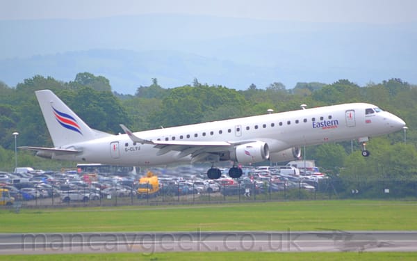 Side view of a white, twin engined jet airliner flying from left to right at a very low altitude