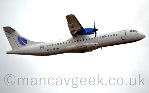 Side view of a white, high-winged, twin propellor-engined airliner flying from left to right at a very low altitude